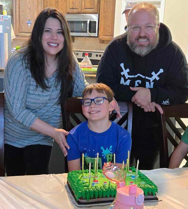 Balkum parents watching son blow out candles.