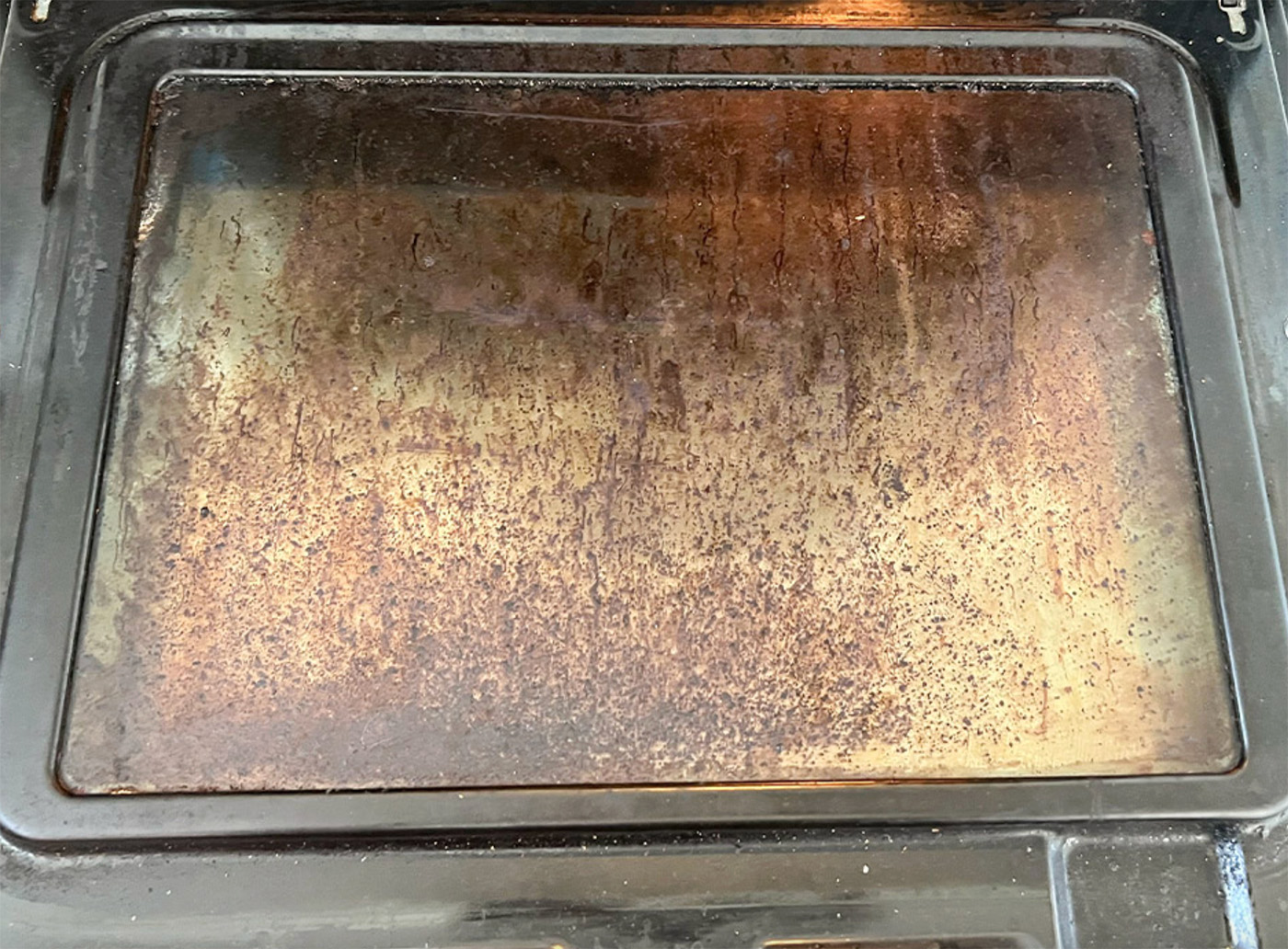 Dirty oven glass door with baked-on grease buildup