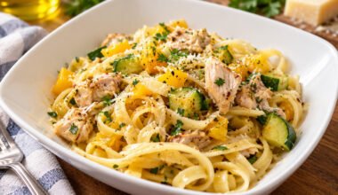 Bowl of garlic olive oil chicken fettuccine with zucchini, yellow squash, bell pepper and Parmesan cheese