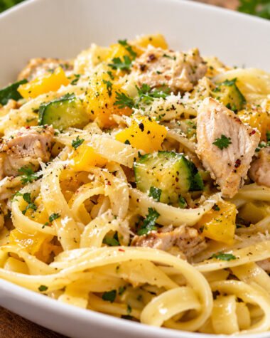 Bowl of garlic olive oil chicken fettuccine with zucchini, yellow squash, bell pepper and Parmesan cheese